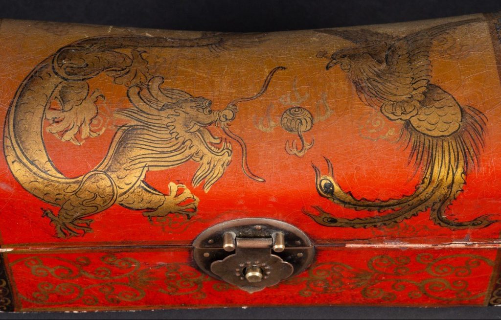 A dragon and a phoenix painted on a Chinese wood-and-leather pillow of the late 19th century or early 20th.