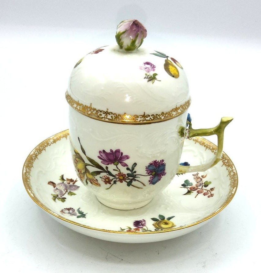 An early Meissen chocolate cup, saucer and lid from around 1740-1760. With a naturalistic decor, a rose bud for the lid knob and a branch for the cup handle.
