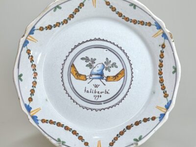 A Phrygian cap held by two hands symbolize liberty and the unity of those defending it. A Nevers revolutionary plate dated 1790.