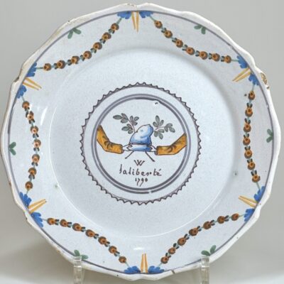 A Phrygian cap held by two hands symbolize liberty and the unity of those defending it. A Nevers revolutionary plate dated 1790.