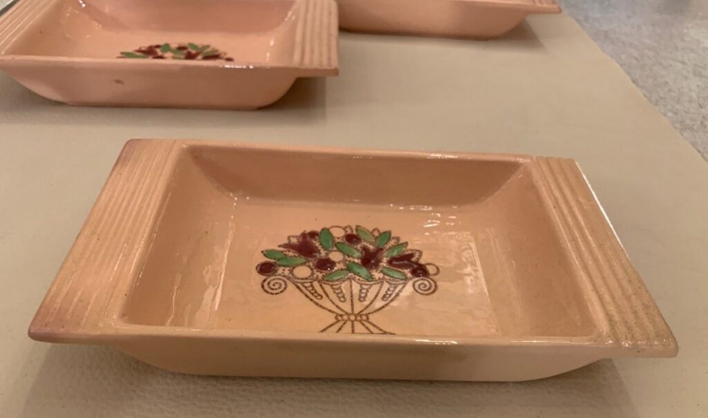 In this Art Deco catchall tray, we clearly see the raised enamels for the flowers and leaves of a stylized bouquet. Brocatelle technique on a powder pink background.