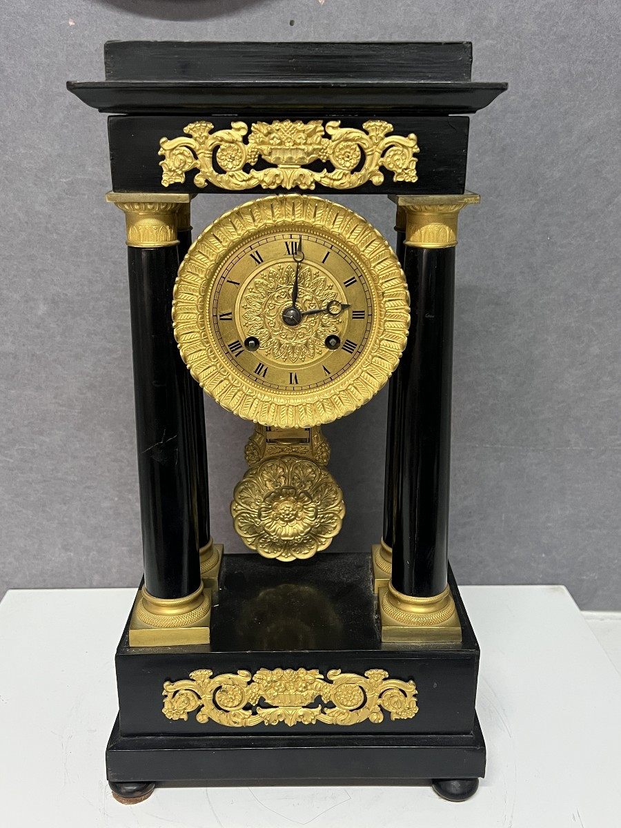 Empire Clock With 4 Columns, Pendulum, In Blackened Wood With Mercury-gilt Bronzes.