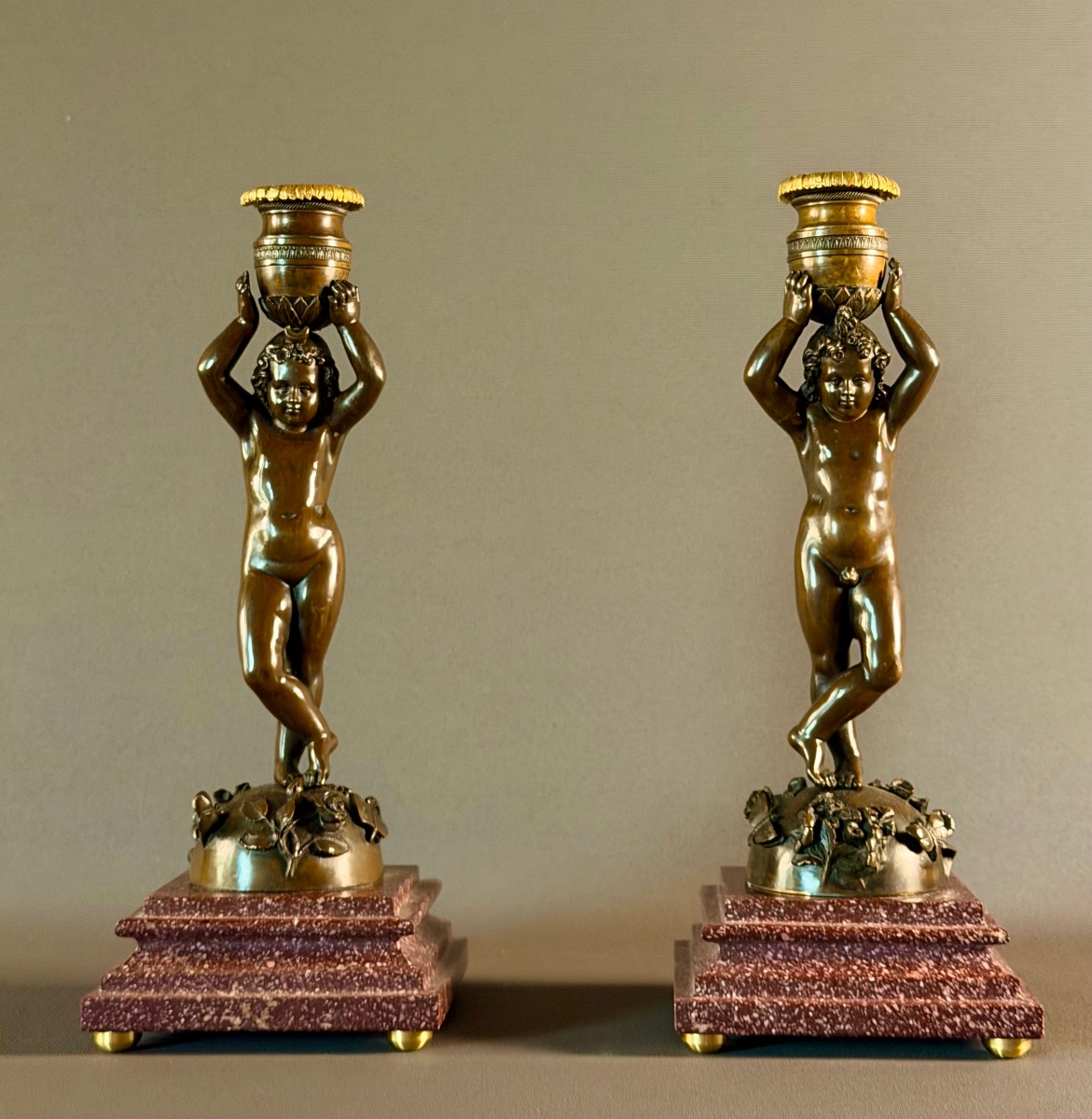 Paire de flambeaux en bronze patiné à décor de putti canéphores. Vers 1850