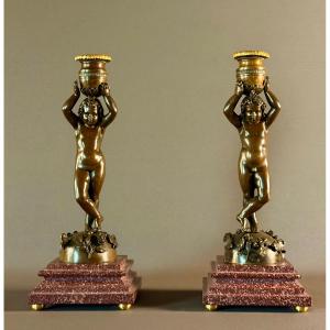 Paire de flambeaux en bronze patiné à décor de putti canéphores. Vers 1850