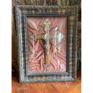 Un Christ en métal argenté sous un verre bombé dans un cadre en trompe l'oeil