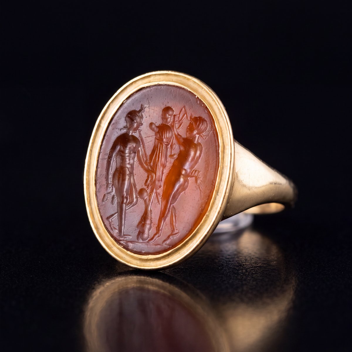 A Gold Ring Set With A Roman Carnelian Intaglio. Two Satyrs Crowning A Trophy.