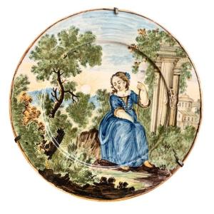 Faïence de Castelli, assiette avec jeune femme au fuseau dans un paysage avec ruines. XVIIIe
