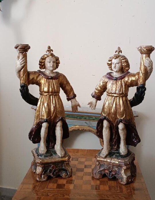 Paire d'anges anciens tenant des bougies, en bois sculpté, laqué et doré