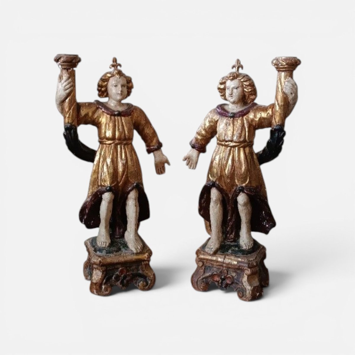 Paire d'anges anciens tenant des bougies, en bois sculpté, laqué et doré