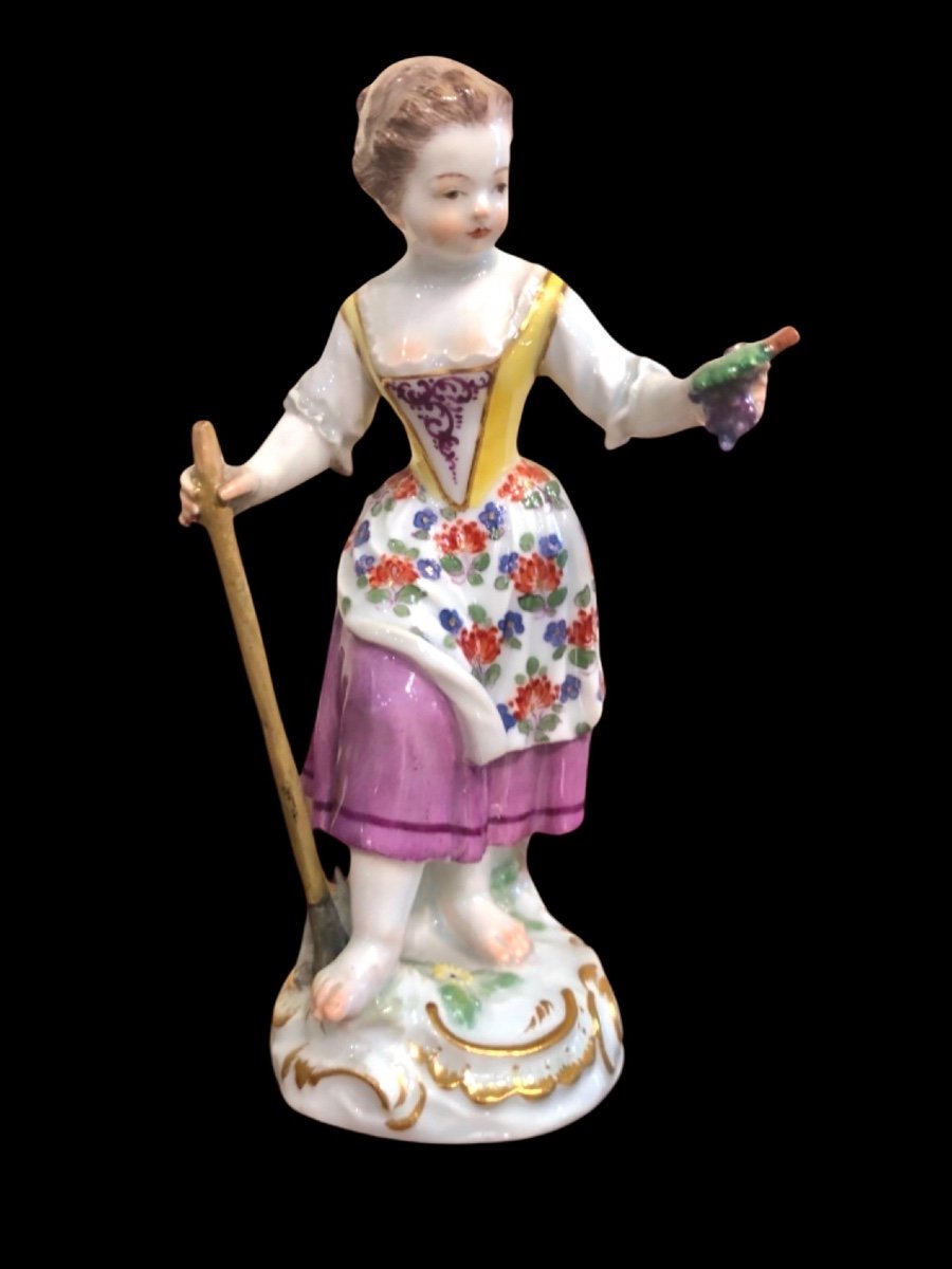 Sculpture en porcelaine, figure d'une paysanne avec un bâton et une grappe de raisin. Meissen. 
