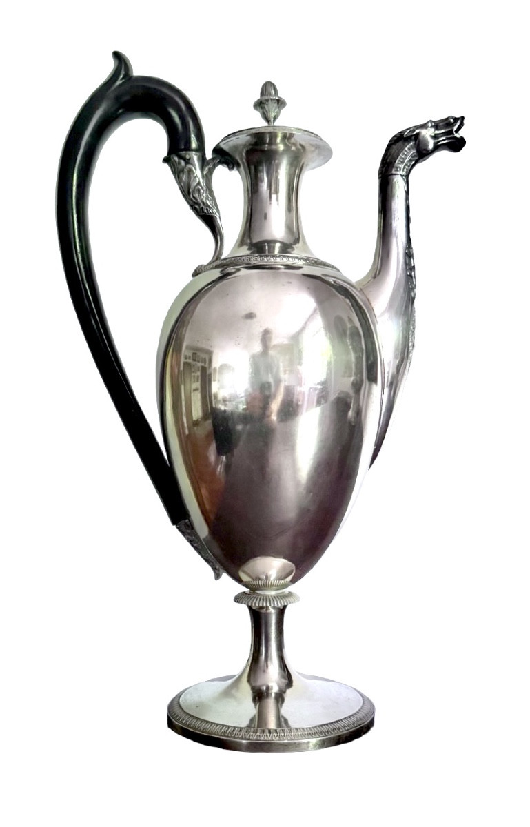 A Silver Coffee Pot With A Pear-shaped Body Resting On A Circular Base Adorned With Lanceolate Leaves.