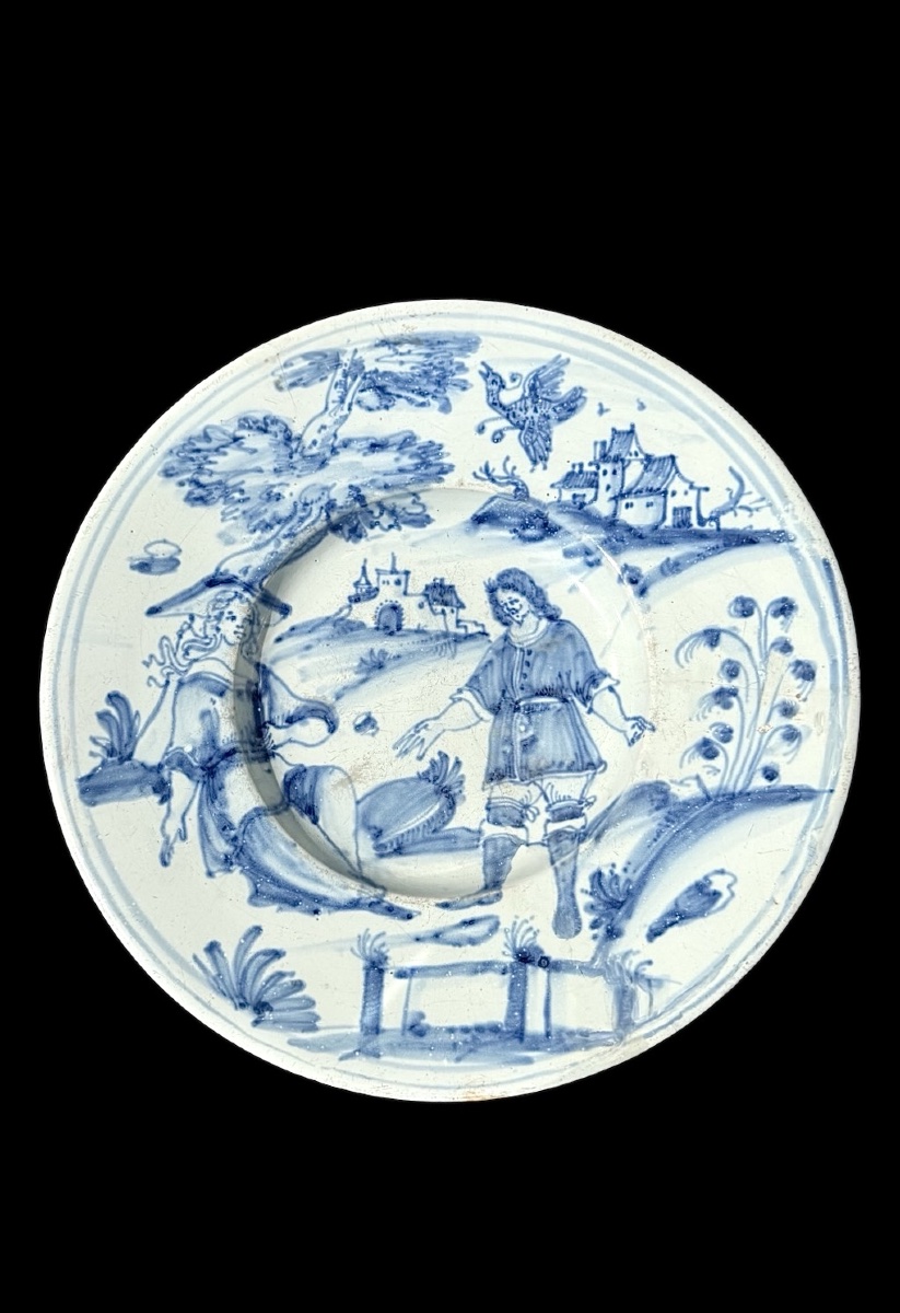 Assiette monochrome en faïence bleue avec deux personnages dans un décor champêtre.Nevers