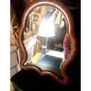 Miroir Louis Philippe de forme chantournée a encadrement de bois de satiné arrondi pied pliant.
