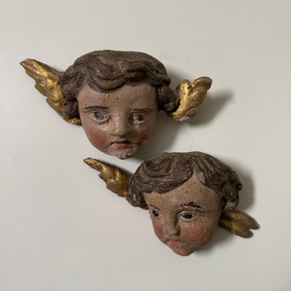 Paire de têtes d'angelots XVIIIe en bois sculpté polychromé avec dorure
