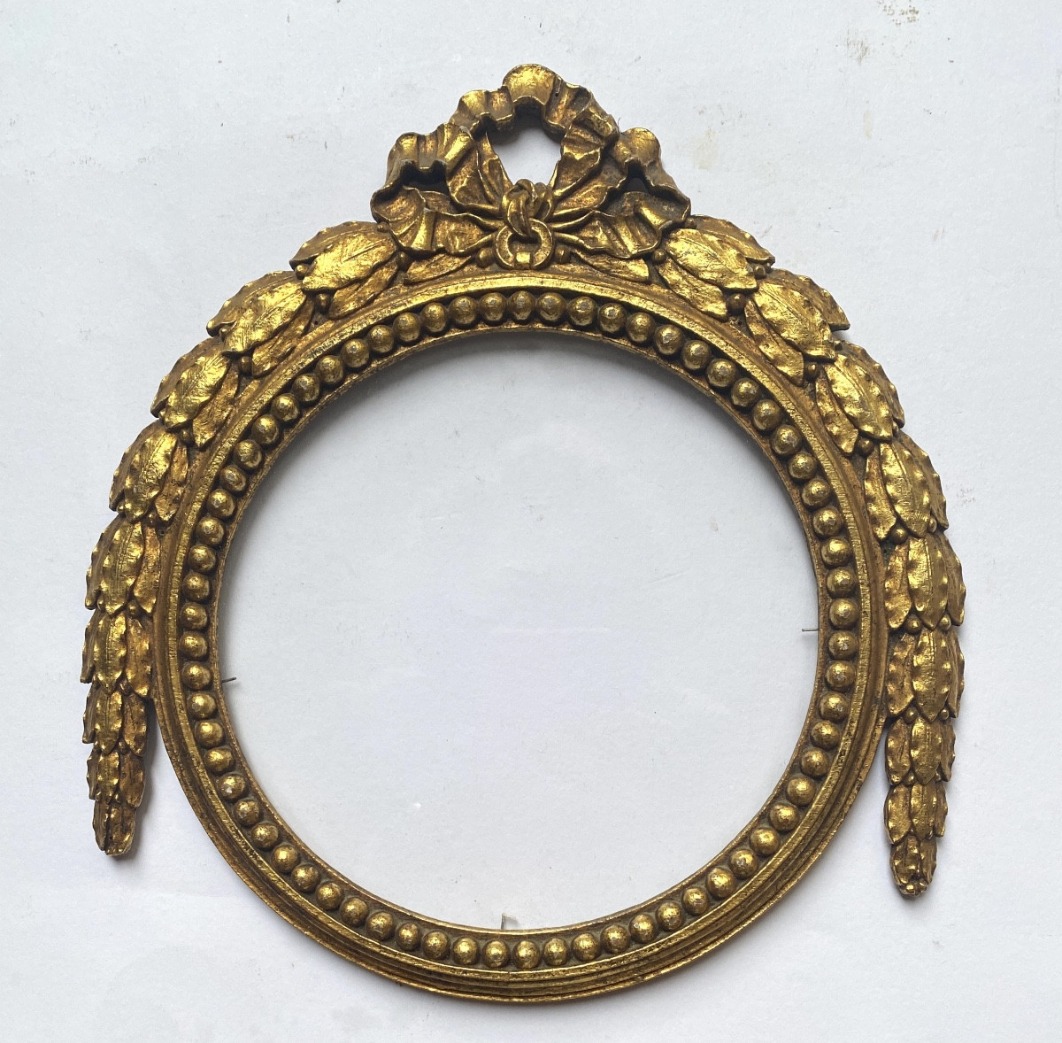 Cadre en bois doré de style Louis XVI. Feuilles de laurier, perles  et ruban noué