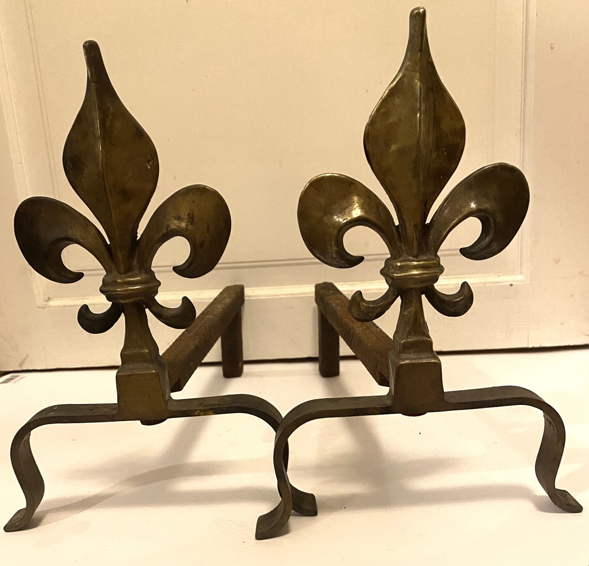 Paire de chenets début XXème. Fleurs de lys en bronze. Piétements en fer. 