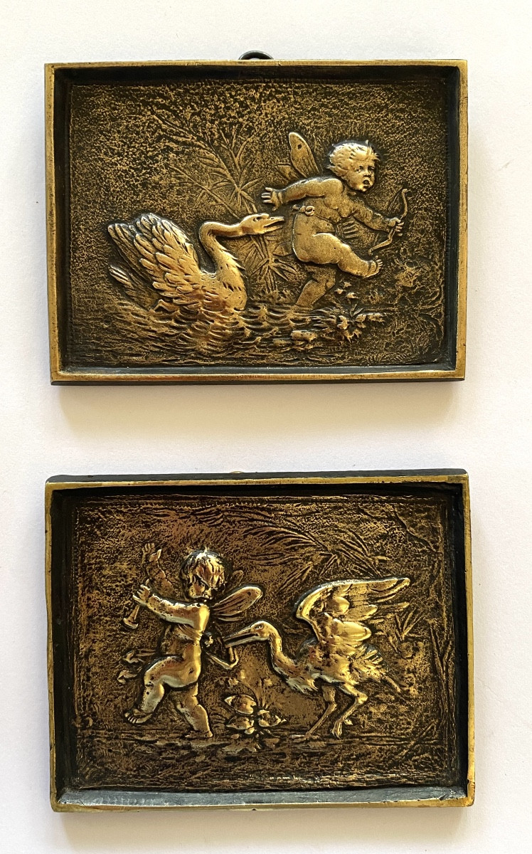 Paire de petits bas-reliefs en bronze XIXème. Angelots poursuivis par un cygne et un échassier.