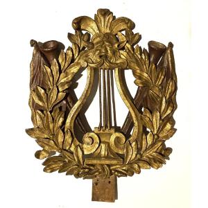 Fronton XVIIIè. Bois sculpté et doré. Mascaron, lyre, hautbois, drapeaux et feuilles de laurier