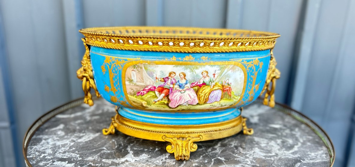 Coupe ovale en porcelaine décor scène galante et fleurs fond bleu céleste, monture bronze doré.