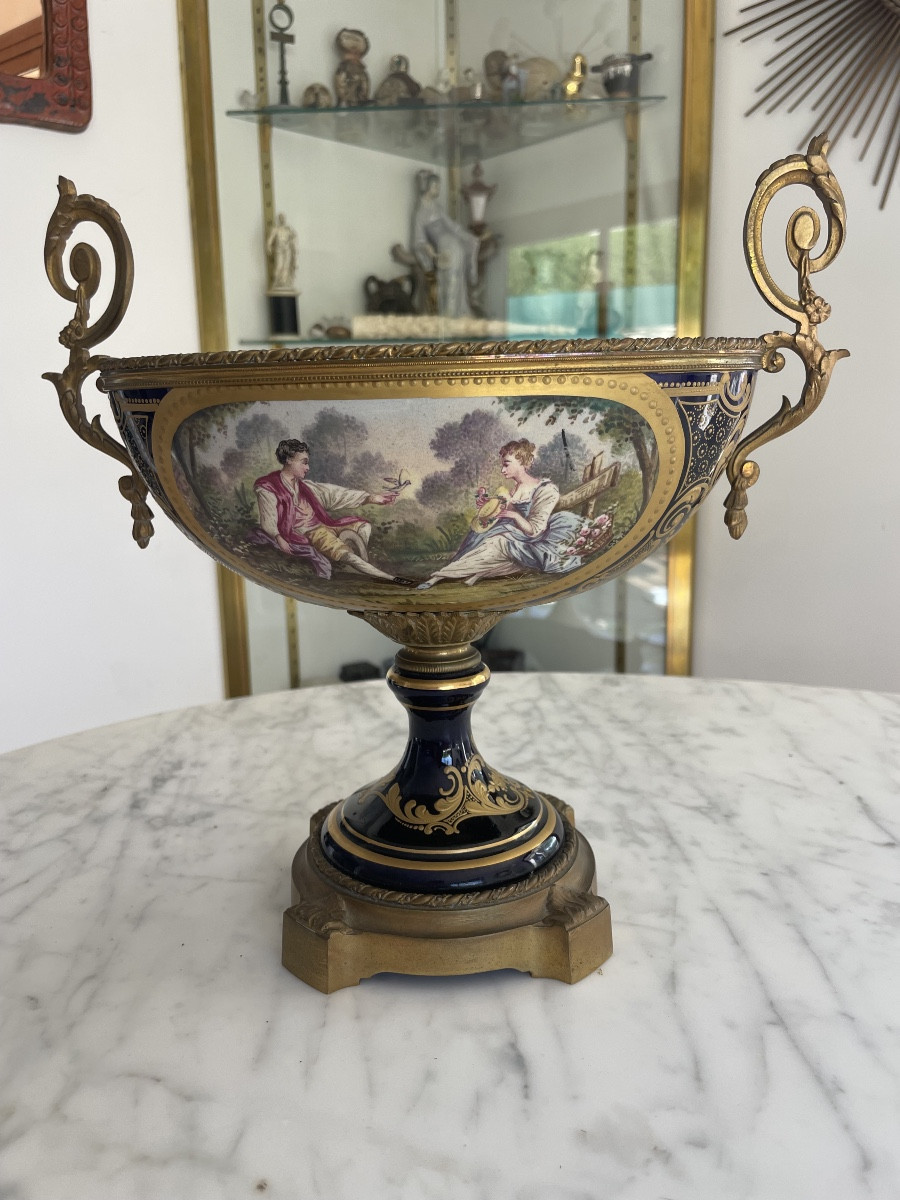 SEVRES, dans le goût.  Coupe en porcelaine émaillée à fond bleu à décor d'une scène animée 