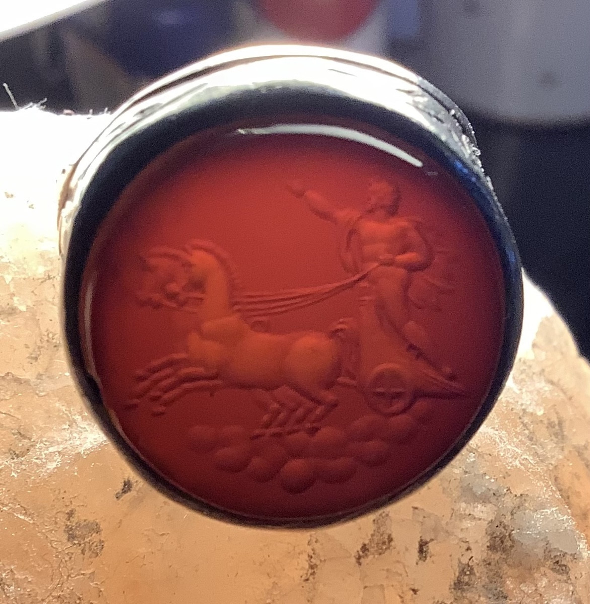 A Silver Ring With An Engraved Red Glass Intaglio Depicts Apollo On A Chariot.