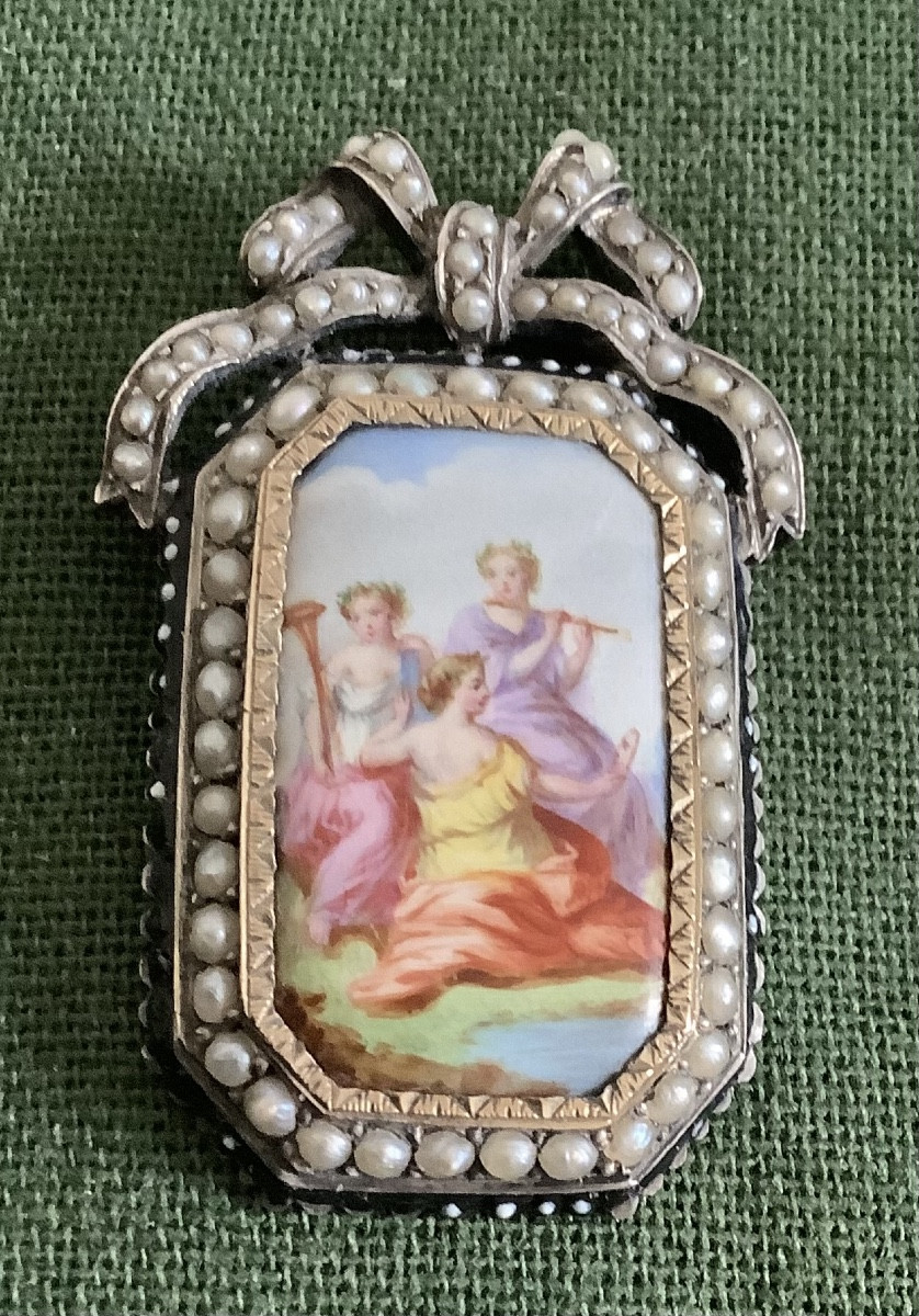Une broche en argent sertie de demi  perles decor de porcelaine représentant 3 musicians