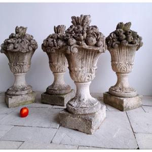 Ensemble de quatre vases garnis de fruits et de fleurs en pierre sculptée