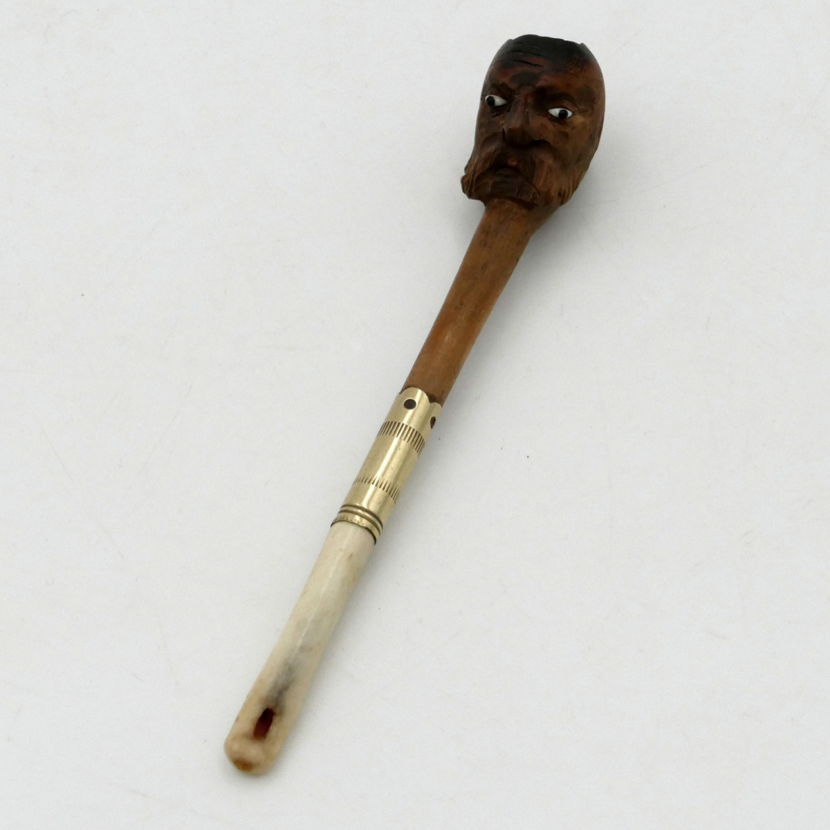 Fume cigarette, tête de vieil homme en bois, os et yeux en verre, début XXe siècle.