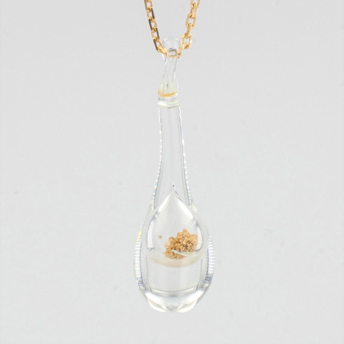 Gold Chain And Its Glass Pendant And Gold Glitter-photo-1