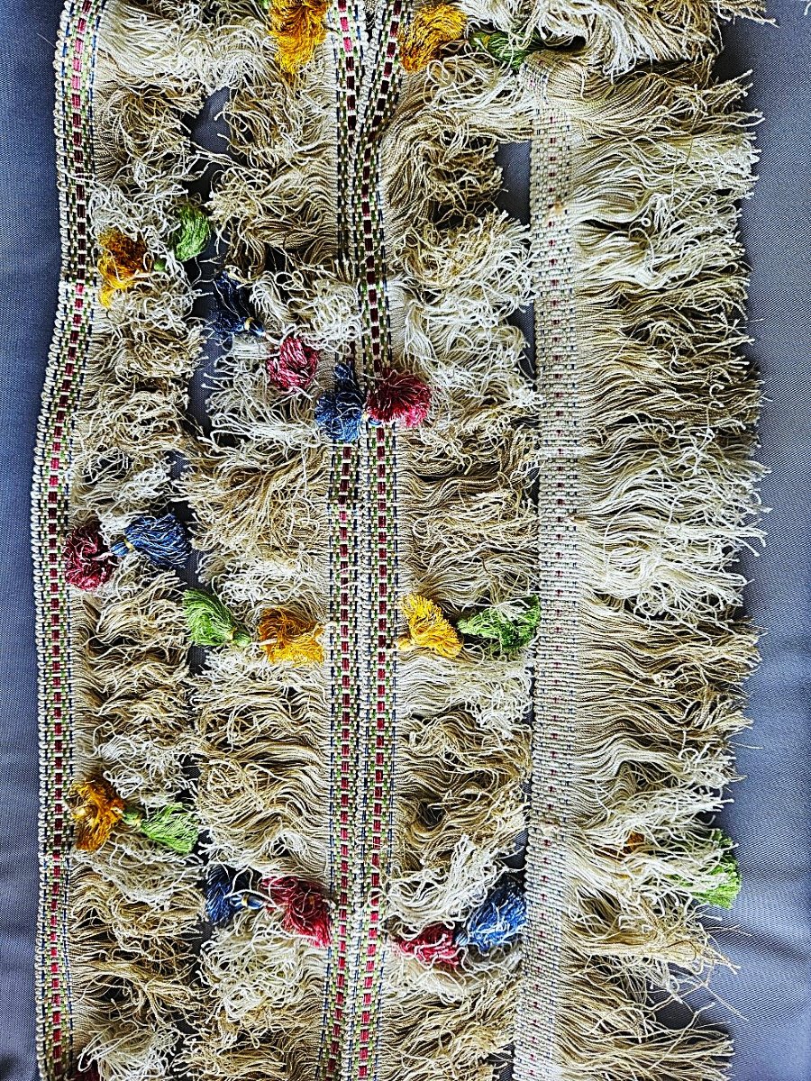 Galon tressé sur fond blanc, rouge et vert / Avec frange blanche et succession de pompons.
