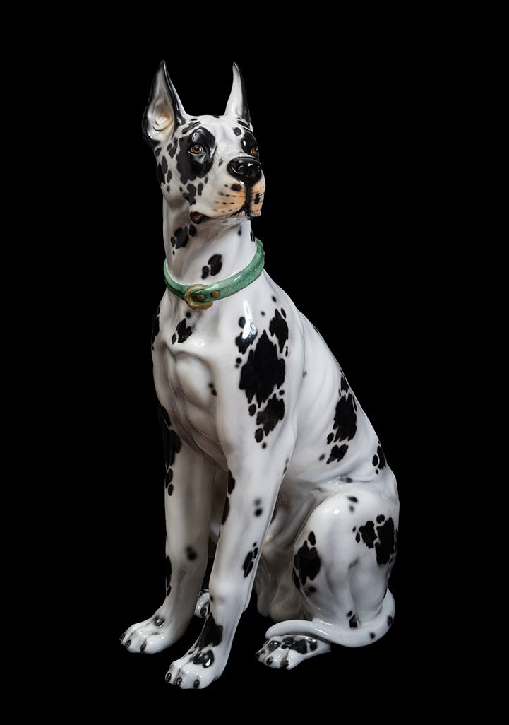 A Polychrome Porcelain Sculpture Depicting A Life-size, Seated Harlequin Great Dane.