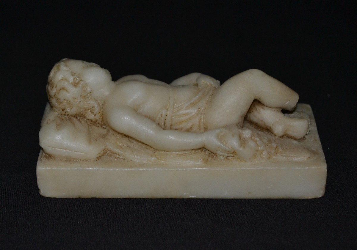 Putti endormi tenant un masque de Silène, sculpté en Albâtre. Europe 19° siècle. 