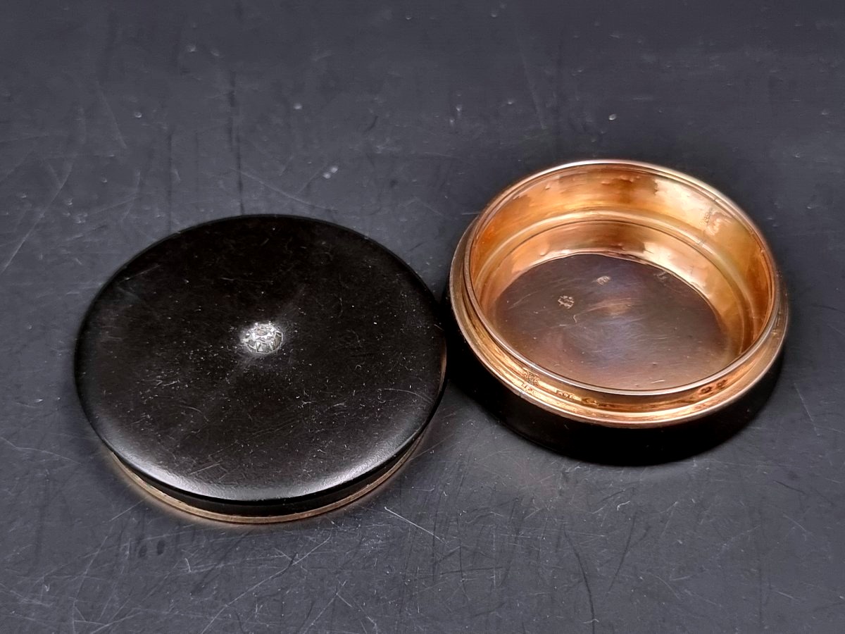 A Circular Box Made Of Composite Material, Set With A Diamond And Featuring A Gold Interior 