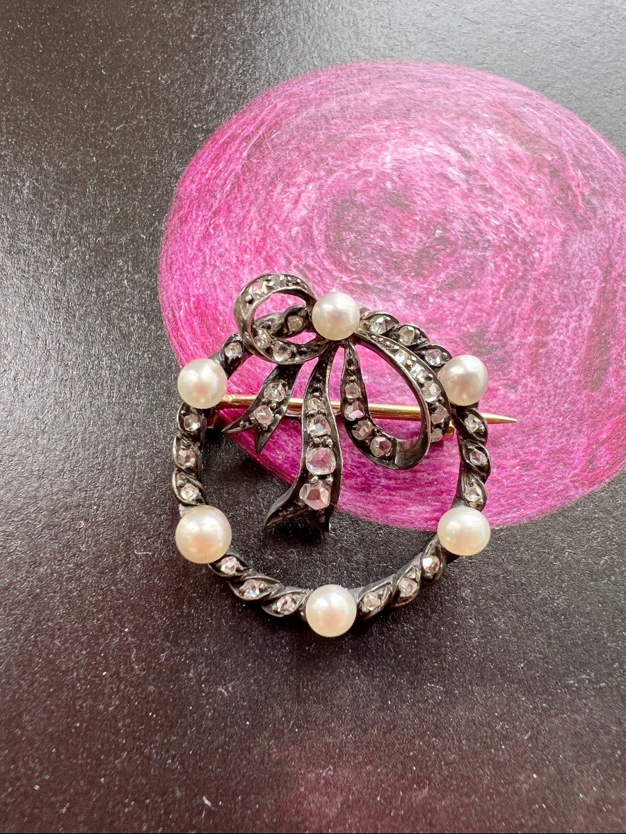 Broche nœud en or jaune 18K (750°/00) ornée d'une perle de culture. PB