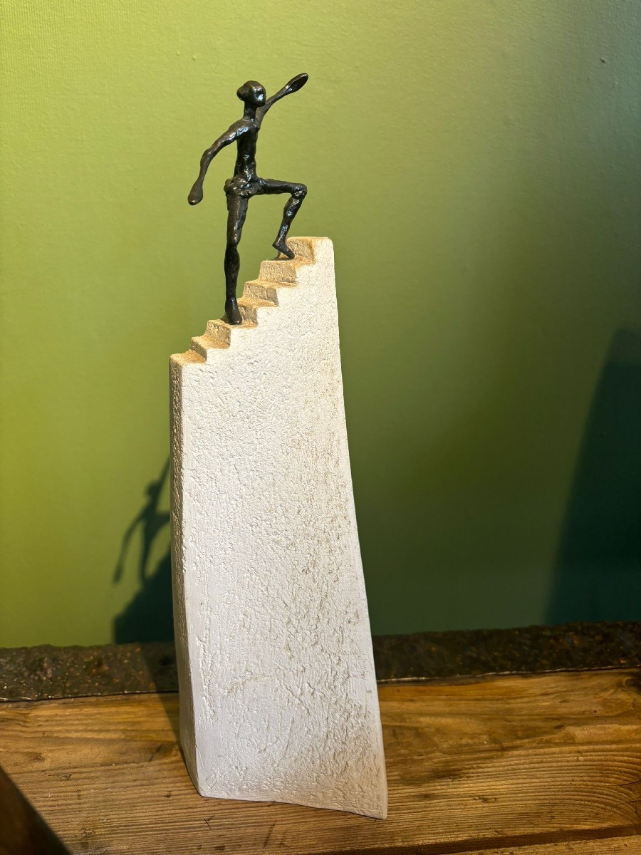 Sculpture contemporaine homme gravissant escalier