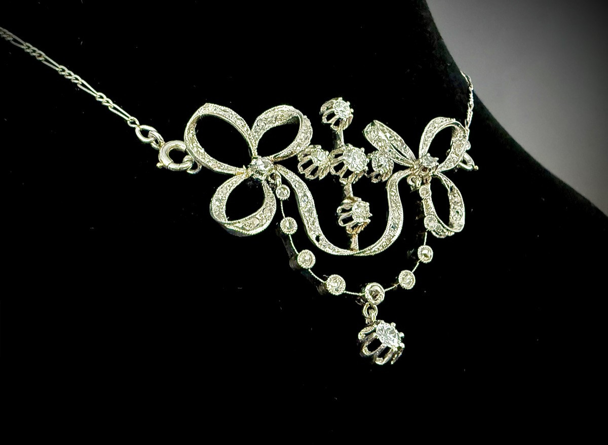 Pendentif et chaîne en platine, belle époque, noeuds de ruban et guirlandes, 1,40ct de diamants
