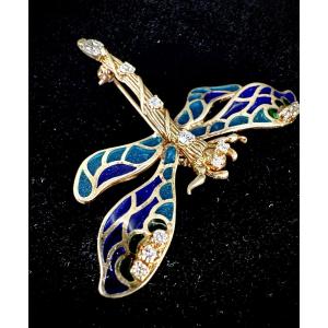Broche libellule en or jaune dont les ailes sont en émail bleu et le corps serti de diamants