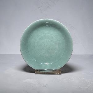 ASSIETTE EN CÉLADON, bord ondulé et décor en relief composé de cercles concentriques formant qu