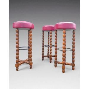 Victor Courtray - 3 tabourets de bar en bois et cuir rouge; entretoises en métal (vers 1930)