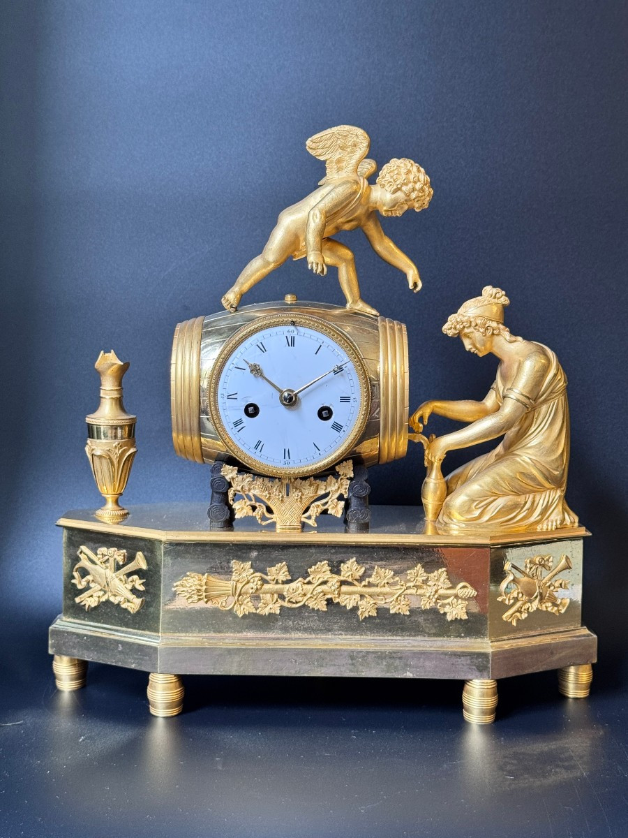 Pendule Empire "jeune femme et cupidon tirant le vin du tonneau" en Bronze doré 