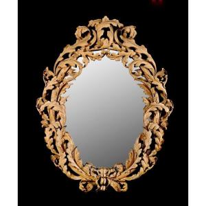 Miroir ovale avec cadre en bois richement sculpté et ajouré de feuilles d’acanthe.