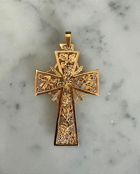 Croix rayonnante à décor de raisins, en or jaune