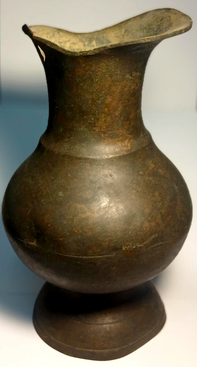 Verseur lombard en cuivre à corps central sphérique orné de trois incisions concentriques.