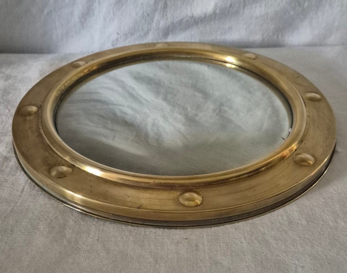 Miroir sorcière dans son cadre "hublot" rond  en laiton. 