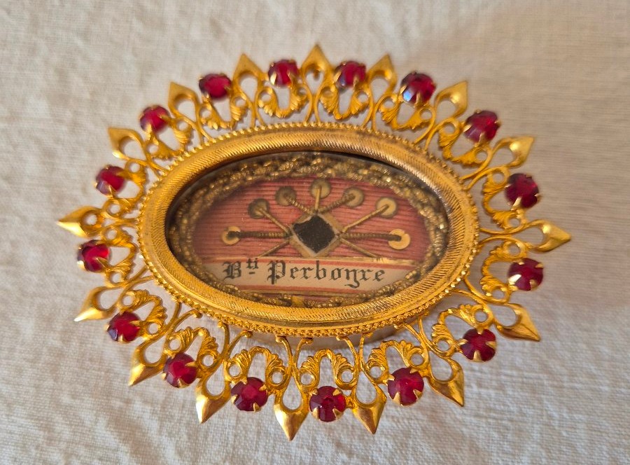 Reliquaire doré ovale en argent doré à  décor rayonnant serti de pierreries rouge grenat