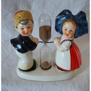 Couple Of Alsatian Children On A Tray Separated By A Glass Hourglass Timer. 