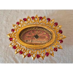 Reliquaire doré ovale en argent doré à décor rayonnant serti de pierreries rouge grenat