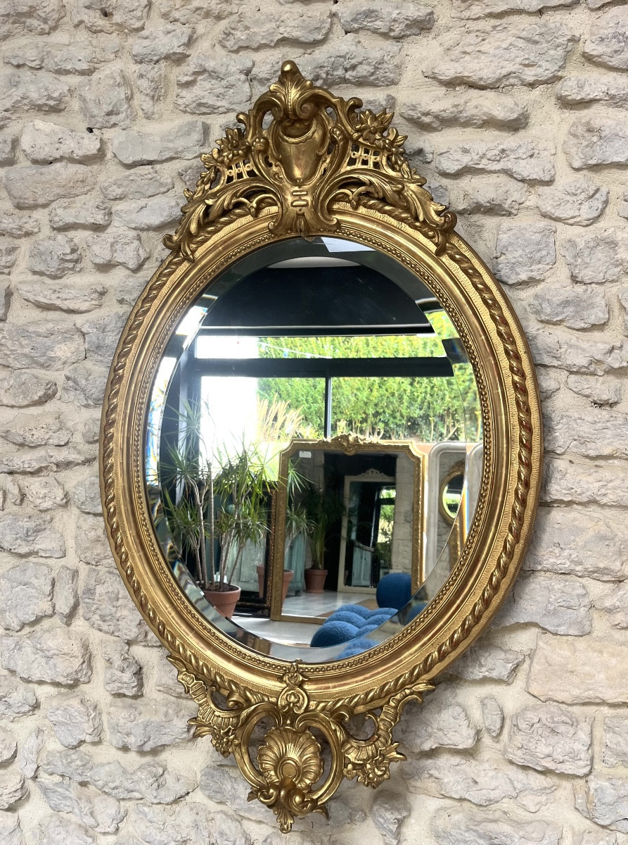 Miroir ancien ovale à frontons et perlé doré à la feuille d’or glace biseautée.