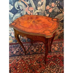 Pretty living room table that can also be used as a work or work table. &nbsp;Louis XV style and late 19th century. In rosewood marquetry, rosewood, precious wood and color. &nbsp;The top, of animated shape, is surrounded by a bronze mold and is decorated with a beautiful work of marquetry representing a quiver and arrows in a bouquet of roses. &nbsp;The lock is in working order. &nbsp;Interior with compartments, rosewood marquetry and mirror. &nbsp;Good original condition.<br />
&nbsp;Delivery possible, please contact us.