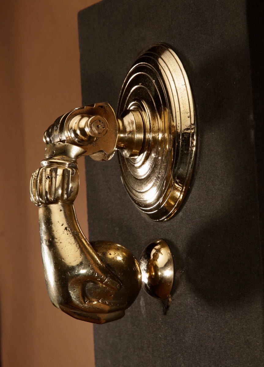  Un heurtoir de porte en bronze de grande taille, représentant une main.